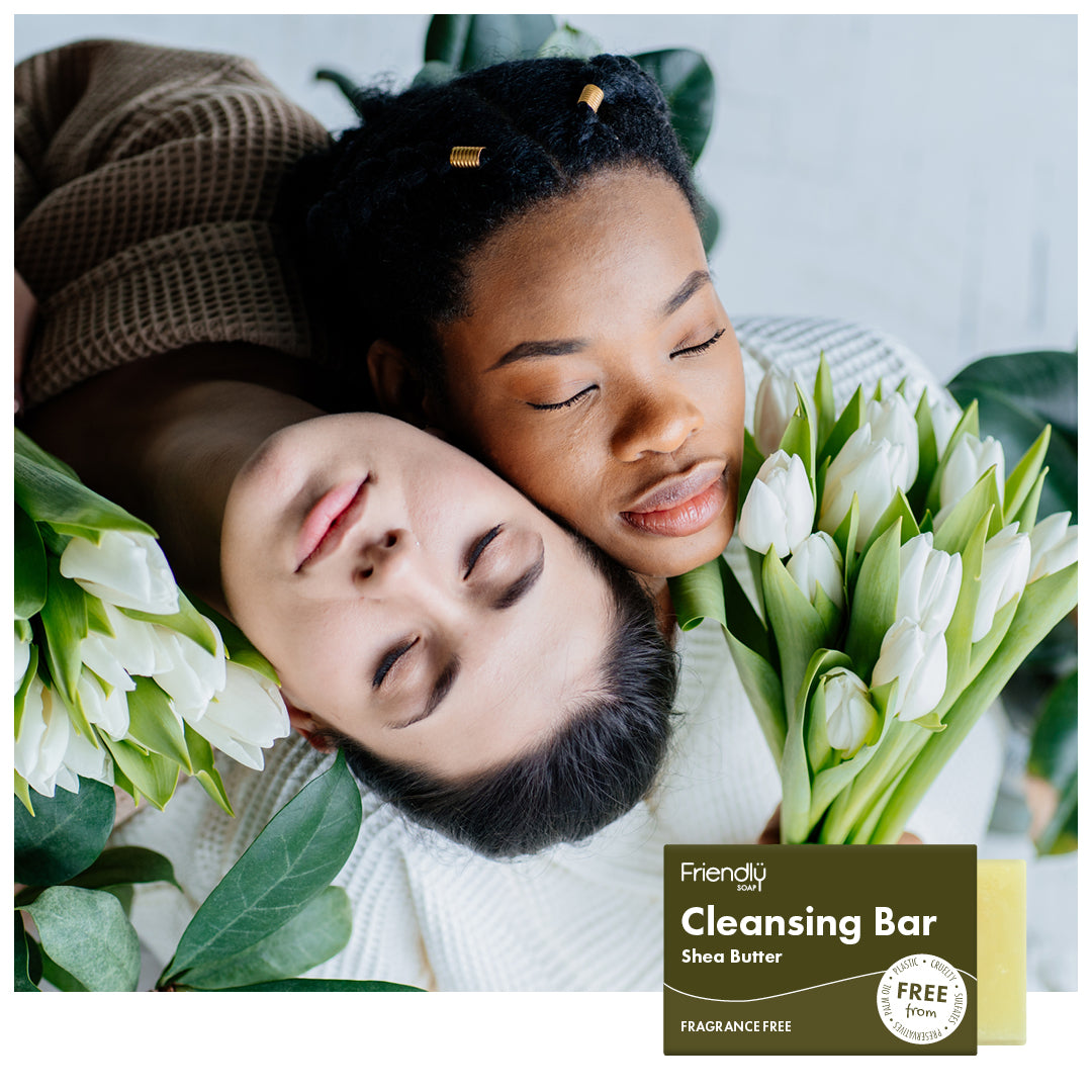 two young women with flowers, lay down with their faces next to each other.