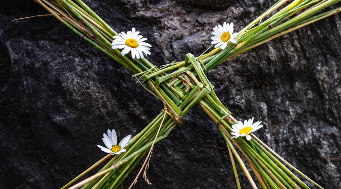 celtic cross made of grass with daisies resting on a rock