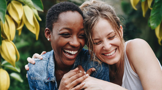 two women laughing together in a ylang ylang orchard