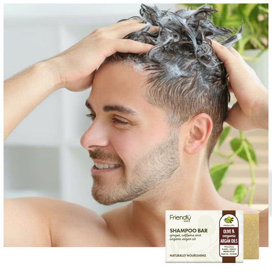 a young man smiling and washing his hair in the shower with a friendly soap shampoo bar