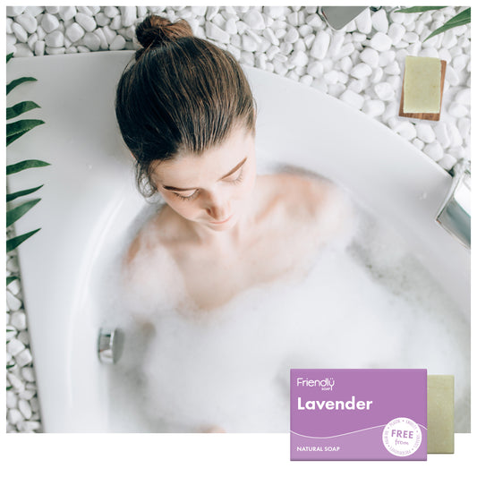 woman relaxing in the bath surrounded by white stones and a friendly soap lavender bar