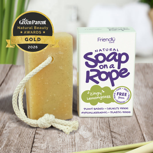 A bar of award winning 'zingy' lemongrass natural soap on a rope next to its white and purple packaging box, displayed on a rustic wooden surface with a Gold 2026 award badge from The Green Parent.