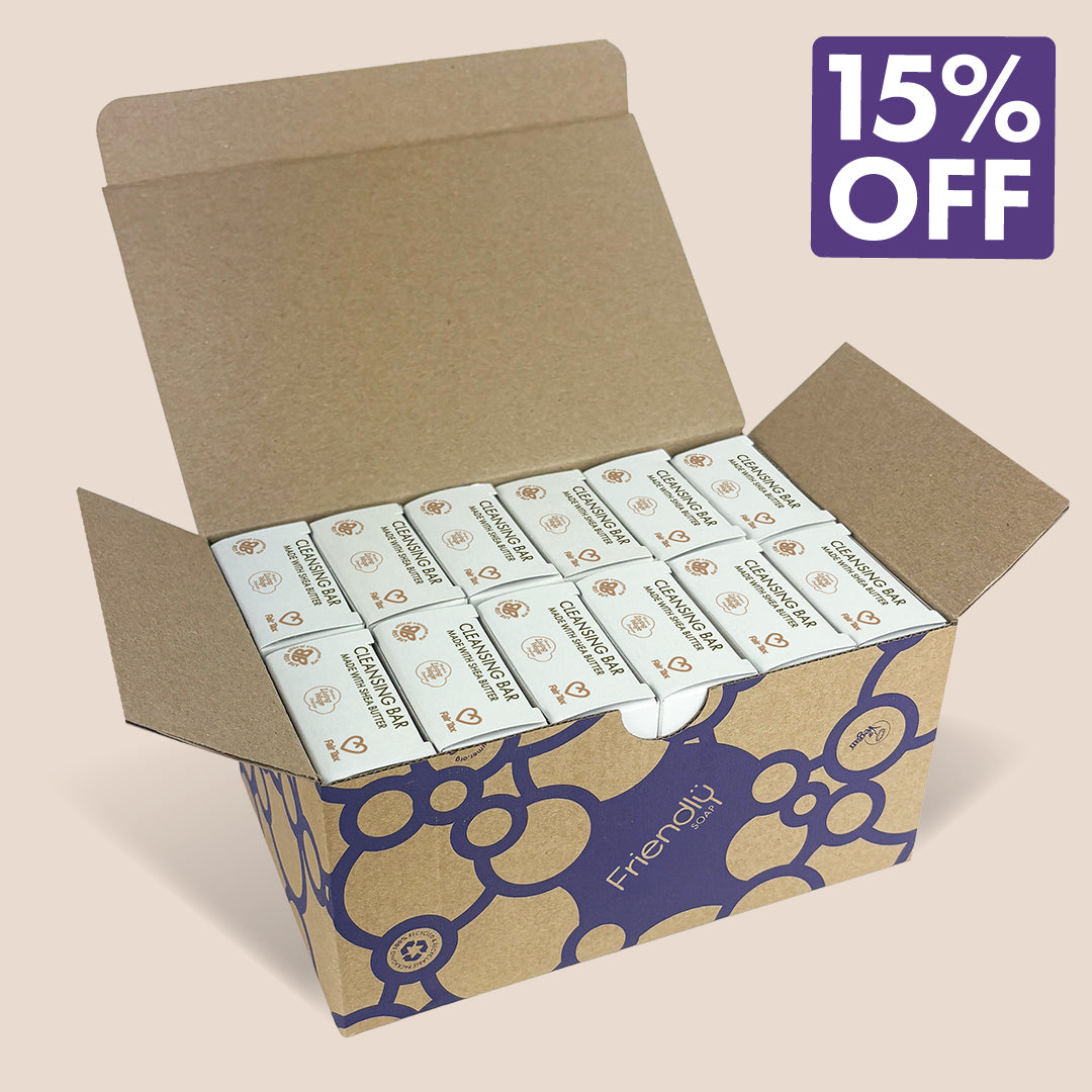 An open kraft cardboard box containing 12 patchouli cleansing bars '15% OFF' badge in the top right corner. The box has a blue bubble pattern and the brand name 'Friendly soap' printed on the front.