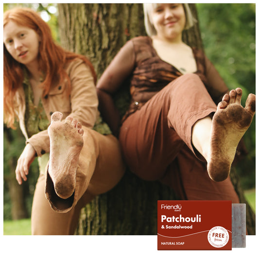 two happy hippy women showing their bare feet in the woods - patchouli and sandalwood natural soap