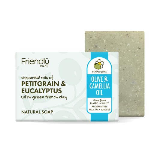 A bar of petitgrain and eucalyptus Friendly soap with its retail packaging, shown against a plain white background. The soap bar is a natural greenish-gray clay color, and the packaging features a white and bright blue design with text identifying it as containing 'Olive & Camellia Oil'.