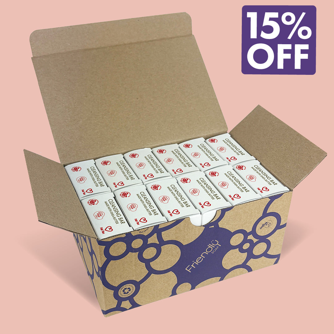 An open brown cardboard box containing 12 Ylang Ylang cleansing bars. The box has a dark blue floral pattern and the brand name 'Friendly Soap' is visible.