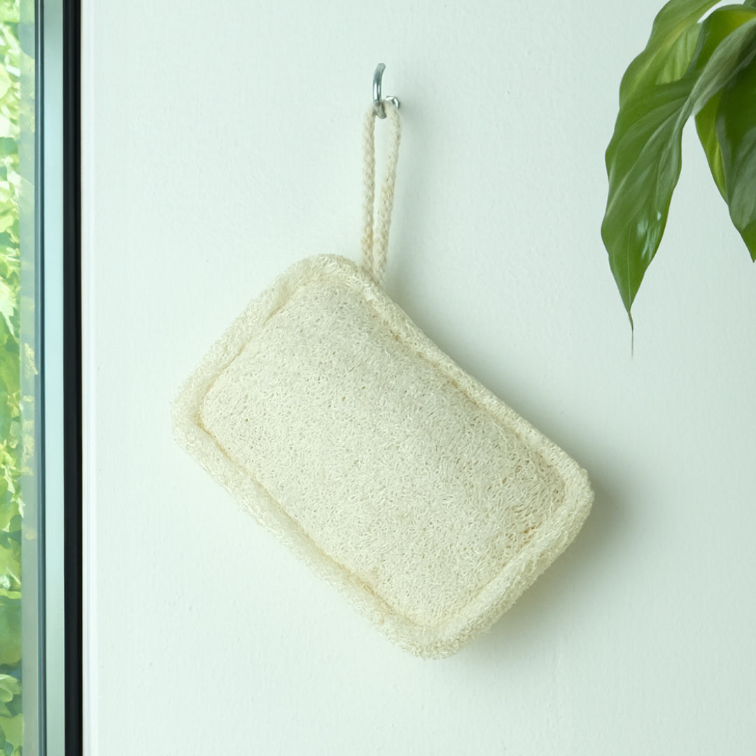 small loofah body exfoliator hanging up to dry after use